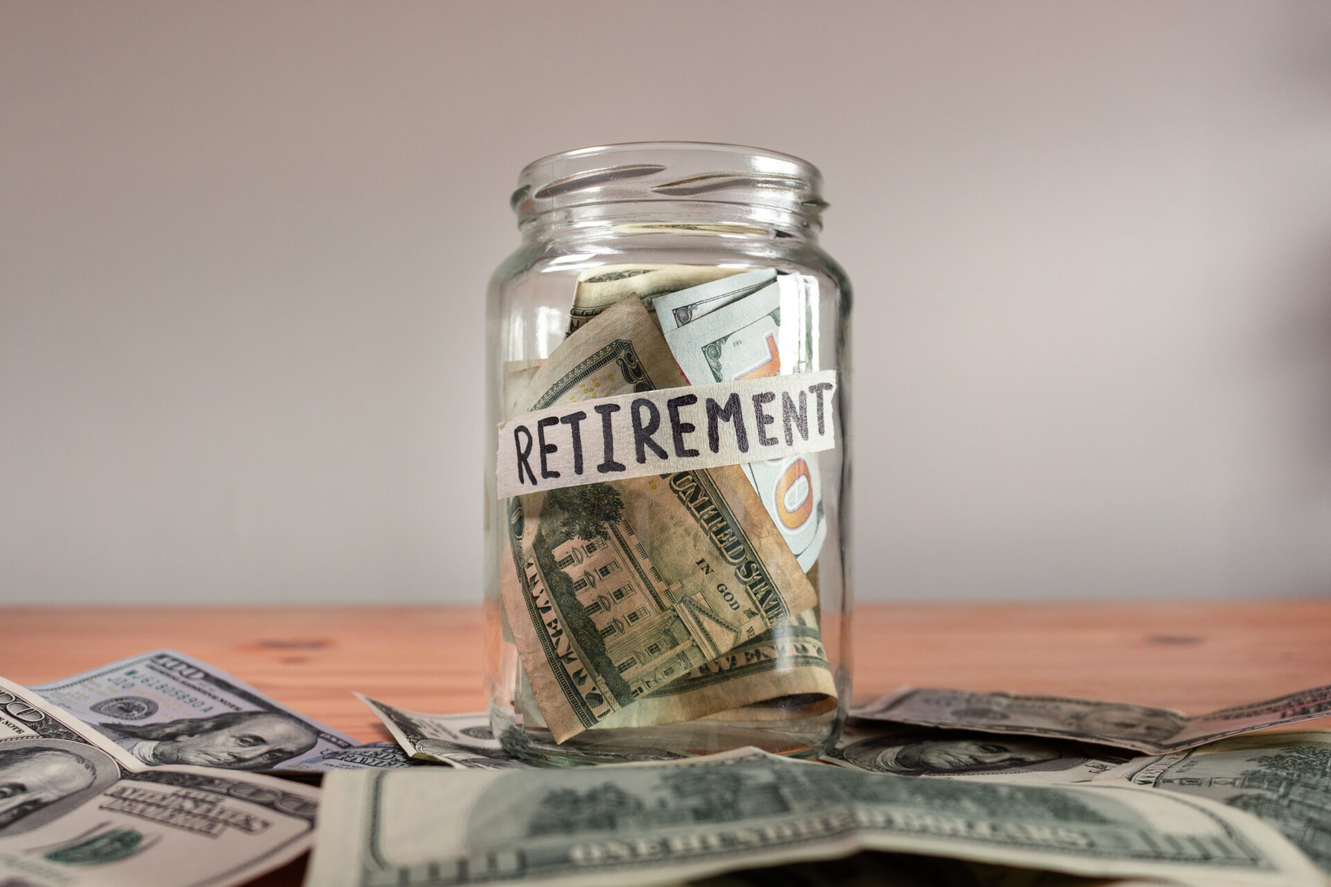 The US Dollar bills in a glass jar labeled "retirement"